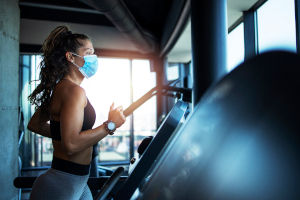 masked woman running on a treadmill